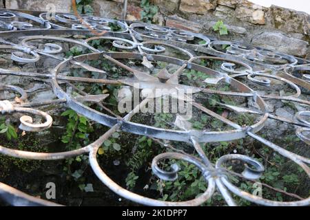 Der Brunnendeckel mit einem verzierten Muster schützt einen alten Brunnen in Monterey, CA. Ein alter Brunnen im Garten eines historischen Hauses spiegelt die Handwerkskunst von d wider Stockfoto