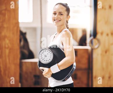 Fitness-Frau mit Gewichtverlustskala im Fitnessstudio, Sportstudio und Fitnessclub. Porträt einer glücklichen, starken und lächelnden Frau mit gesunder Ernährung, aktiv Stockfoto