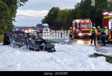 Werne, Deutschland. 17. September 2022. In einem See aus Löschschaum neben der Autobahn A1 steht noch immer ein komplett ausgebranntes, zerstörtes Auto. Ein Fahrer verließ die Straße bei Werne (Kreis Unna) mit seinem Auto und kippte. Der Mann und seine Beifahrerin waren am Samstagabend mit Rettungshubschraubern mit schweren Verletzungen ins Krankenhaus geflogen worden. Ein Hund, der auch ein Passagier war, war am Unfallort gestorben. Quelle: Michael Neumann/dpa/Alamy Live News Stockfoto