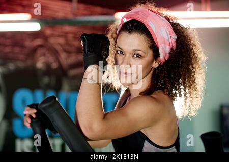 Sehen aus wie ein Schönheitszug wie ein Tier. Eine junge Frau, die mit einem Stepping-Gerät im Fitnessstudio trainiert. Stockfoto