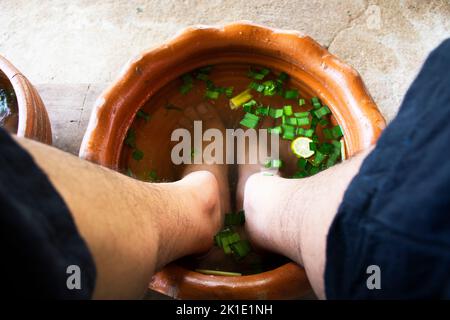 Thai Männer Menschen sitzen entspannen und Fuß Bad im Becken mit Kräuterkräuter vor lokalen Spa-Massagen thai-Stil Koh Kret Insel in Pak Kret Stadt in Nonthaburi, Stockfoto