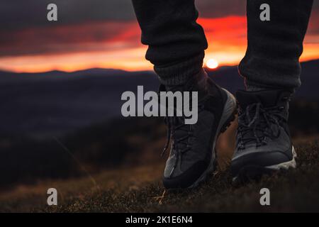 Person steht in Wanderschuhen im Freien vor dem wunderschönen Sonnenuntergang Stockfoto