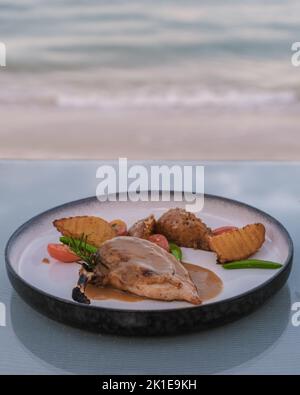 Gegrillte Lammfleisch-Rippchen auf einem Teller mit gebackenen Kartoffeln, Abendessen am Strand Stockfoto