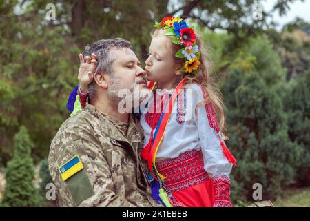 Porträt eines ukrainischen Soldaten mit seiner kleinen Tochter. Lang erwartete Sitzung. Stockfoto