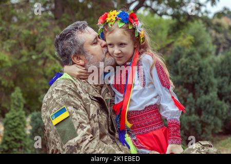 Porträt eines ukrainischen Soldaten mit seiner kleinen Tochter. Lang erwartete Sitzung. Stockfoto