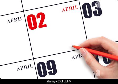 2. Tage im April. Eine Hand, die einen roten Stift hält und auf das Kalenderdatum April 2 zeigt. Rotes Kalenderdatum, Platz zum Kopieren, Modell. Frühlingsmonat, Tag der Stockfoto