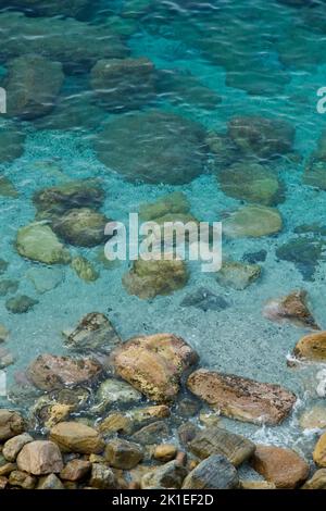 Eine vertikale Aufnahme der Felsen an einem der Ufer des Mittelmeers an einem sonnigen Tag Stockfoto