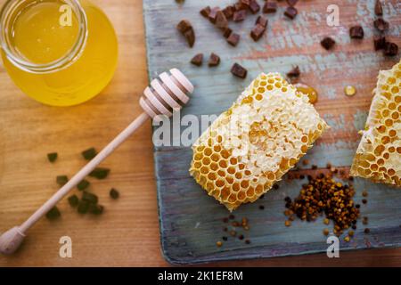 Honig Hintergrund. Süßer Honig im Glas, Waben, Propolis und Pollen auf dem Tisch. Stockfoto