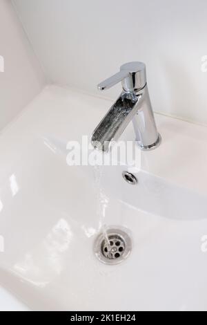 Moderner Wasserhahn mit Wasser aus dem Waschbecken Stockfoto