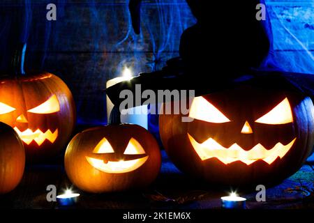 Festliche mystische halloween-Innenausstattung. Kürbis, Spinnennetz, brennende Kerzen, Spinnen auf dunklem Holzhintergrund Stockfoto