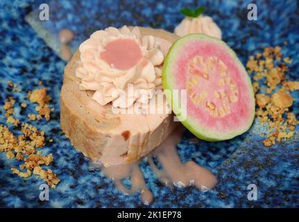 Guava-Rollkuchen auf blauem Teller auf hellem Hintergrund mit reifen Guava-Früchten Stockfoto