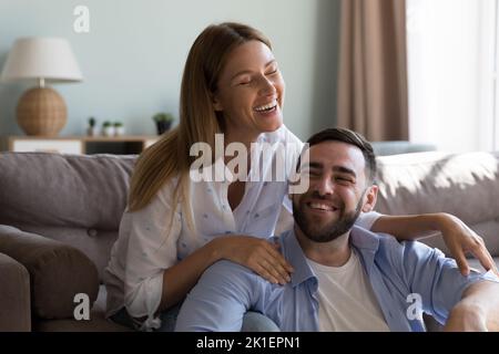 Fröhliches Ehepaar, das im Wohnzimmer redet und lacht Stockfoto