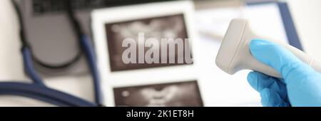 Arzt hält Ultraschallsonde vor dem Hintergrund von Bildern und medizinischen Dokumenten Nahaufnahme Stockfoto