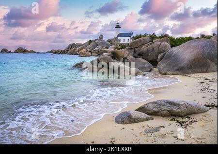 Der Leuchtturm von Pontusval, der sich an einem felsigen Punkt im Norden von Finistere in der Bretagne befindet, überblickt bei Sonnenaufgang ein Meer aus transparentem türkisfarbenem Wasser Stockfoto