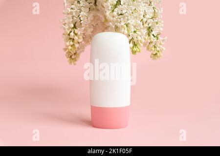 Mockup weiße kosmetische Tube Flasche mit rosa Schraubverschluss und weißen Fliederblüten auf rosa Hintergrund. Täglich feuchtigkeitsspendende Creme, Gel, Hautpflege, Sonnencreme, Stockfoto