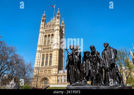 Die Statue der Bürger von Calais, von Auguste Rodin, fertiggestellt 1889, außerhalb des Houses of Parliament, London, Großbritannien. Der Victoria Tower hat eine Union Ja Stockfoto