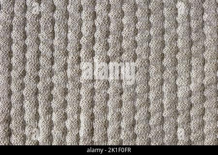 Gestrickter beiger Hintergrund. Große Strickware mit Muster. Nahaufnahme einer Strickdecke Stockfoto