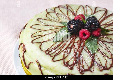 Nahaufnahme eines ganzen runden Cassata Siciliana Kuchens mit grünem Puderzucker und frischen Waldfrüchten auf der Oberseite Stockfoto