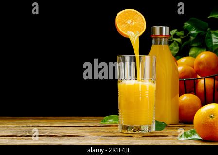 Orangensaft, der auf dunklem Grund in das Glas gießt. Frischer Bio-Orangensaft Stockfoto