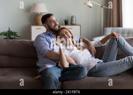 Fröhliches verträumtes Ehepaar, das sich auf dem Sofa entspannen kann Stockfoto