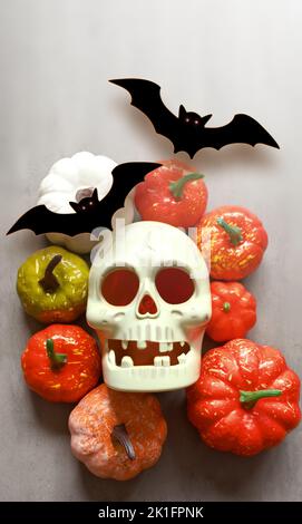Feiertage, Dekoration und Party-Konzept -skull, schwarze Fledermäuse und Kürbisse halloween auf grauem Hintergrund. Stockfoto