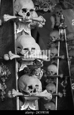 Eine Graustufenaufnahme von gestapelten Schädeln und Knochen im Sedlec-Beinhaus in Kutna Hora, Tschechische Republik Stockfoto