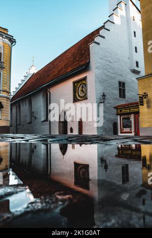 Die Kirche des Heiligen Geistes ist eine mittelalterliche lutherische Kirche in der Altstadt von Tallinn, Estland. Spiegelungen der Kirche in einer Pfütze. Stockfoto