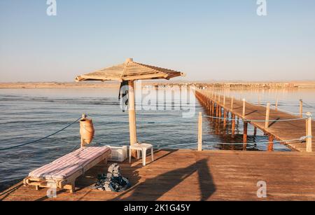 Sonnenschirm aus Holz, Sonnenliege und Tauchgewichte auf einer Pier-Plattform, Marsa Alam, Ägypten. Stockfoto