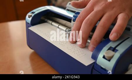 Blinder Mann mit Brailleschrift-Schreibmaschine. Stockfoto
