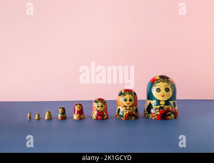 Russische Puppen auch als matryoschka oder babushka auf einem rosa und blauen Hintergrund gestapelt bekannt. Minimalkonzept. Stockfoto