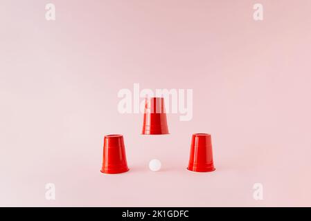 Drei rote Kunststoff-Bier-Pong-Tassen mit weißem Ball unter der Mitte angehoben Tasse. Stockfoto