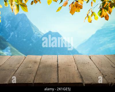 Herbsthintergrund. Sonniger Tag mit Blick auf die Berge und Holzterrasse. Leerer Holztisch in der Natur Stockfoto