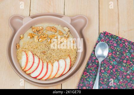 Veganer Grießbrei mit Vollkorn. Gesundes, süßes Frühstück für Kinder. Leckeres Mittagessen voller Kohlenhydrate. Äpfel, Walnüsse. Stockfoto