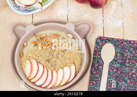 Veganer Grießbrei mit Vollkorn. Gesundes, süßes Frühstück für Kinder. Leckeres Mittagessen voller Kohlenhydrate. Äpfel, Walnüsse. Stockfoto