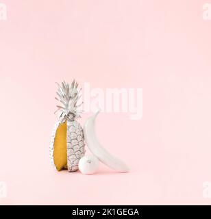 Frische Ananas, Banane und Zitrone in weiß auf rosa Hintergrund gefärbt. Minimales sommerliches Essenskonzept. Stockfoto
