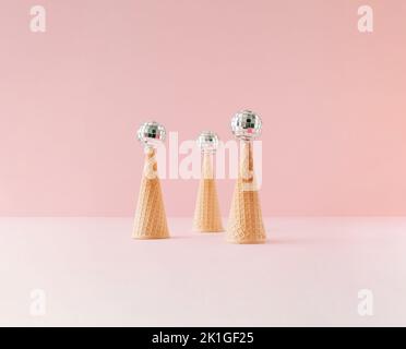 Drei Eiszapfen, die auf den Kopf gestellt wurden, mit Discokugeln auf der Oberseite. Minimales Sommerkonzept. Stockfoto