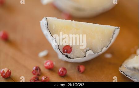 Eine Nahansicht der belper-Kugeln mit Knoblauch und rosa Pfeffer in Holzasche. Schweizer Käse. Milchig fermentierter Käse. SDOF Stockfoto