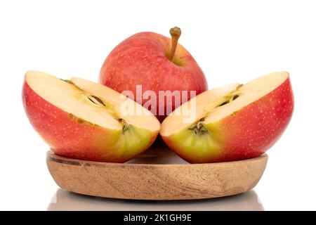 Eine ganze und zwei Hälften saftiger roter Äpfel auf einem Holzteller, Makro, isoliert auf weißem Hintergrund. Stockfoto