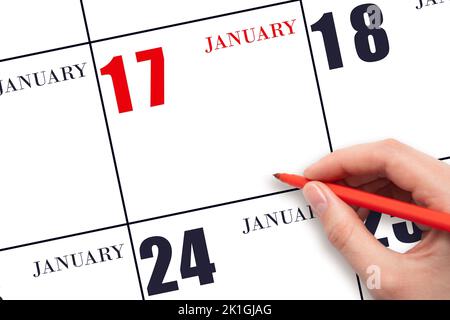 17. Tage im Januar. Eine Hand, die einen roten Stift hält und auf das Kalenderdatum Januar 17 zeigt. Rotes Kalenderdatum, Platz zum Kopieren, Modell. Winter Monat, Tag o Stockfoto