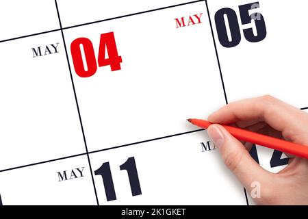 4. Tage im Mai. Eine Hand, die einen roten Stift hält und auf das Kalenderdatum Mai 4 zeigt. Rotes Kalenderdatum, Platz zum Kopieren, Modell. Frühling Monat, Tag des Jahres Stockfoto