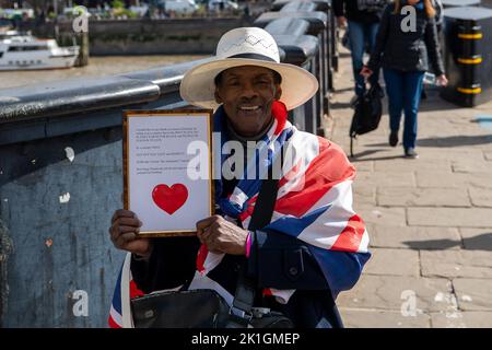 Westminster, London, Großbritannien. 18.. September 2022. Ein Mann hält eine Botschaft für die Königin und König Charles hoch. Mourners überqueren die Lambeth Bridge kurz vor dem Betreten der Victoria Tower Gardens. Über Nacht standen Menschen Schlange, um ihre Majestät die Königin im Staat in der Westminster Hall liegen zu sehen. Viele von ihnen trugen nach einer kalten Nacht Decken, waren aber sehr froh, sich dem Palast von Westminster nähern zu können, um Königin Elizabeth II. Vor ihrer morgigen Beerdigung ihre letzte Ehre zu erweisen. Quelle: Maureen McLean/Alamy Live News Stockfoto