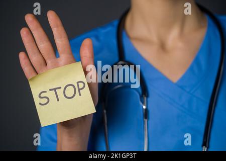 Der Arzt hält ein Papier mit dem Wort „Stopp“ auf der Hand. Stockfoto