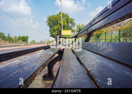 Leere Bahnschild-Tafel, Sitzbank am Bahnhofssteig eines indischen Bergdorfes an einem sonnigen Sommertag. Indianerdorf. Stockfoto