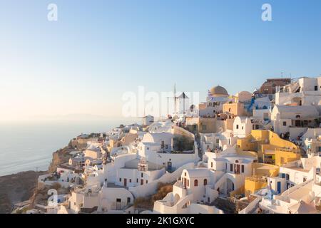 Oia, Griechenland - 11. September 2022: Blick auf die traditionellen weißen Waschhäuser und die Windmühle im beliebten Touristenort Oia am Meer auf einem sonnigen Summe Stockfoto