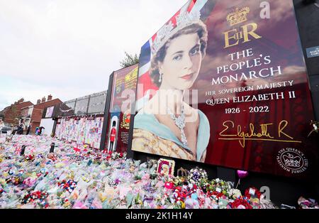 Nach dem Tod des britischen Monarchen legt man Blumen auf ein Wandgemälde, das Königin Elizabeth II. Auf der Shankill Road in Belfast darstellt. Stockfoto