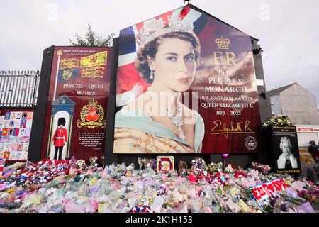 Nach dem Tod des britischen Monarchen legt man Blumen auf ein Wandgemälde, das Königin Elizabeth II. Auf der Shankill Road in Belfast darstellt. Stockfoto