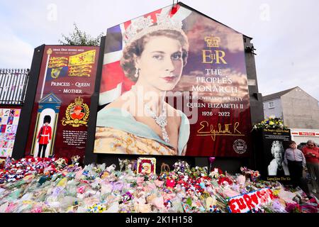 Nach dem Tod des britischen Monarchen legt man Blumen auf ein Wandgemälde, das Königin Elizabeth II. Auf der Shankill Road in Belfast darstellt. Stockfoto