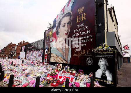 Nach dem Tod des britischen Monarchen legt man Blumen auf ein Wandgemälde, das Königin Elizabeth II. Auf der Shankill Road in Belfast darstellt. Stockfoto