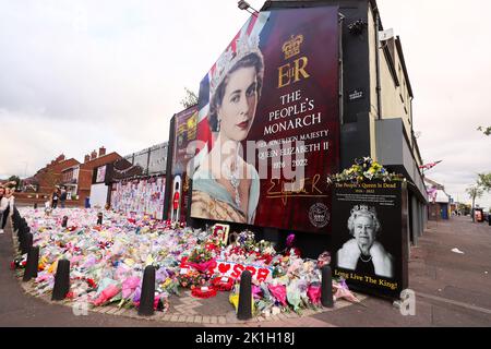Nach dem Tod des britischen Monarchen legt man Blumen auf ein Wandgemälde, das Königin Elizabeth II. Auf der Shankill Road in Belfast darstellt. Stockfoto