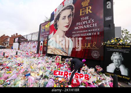 Nach dem Tod des britischen Monarchen legt man Blumen auf ein Wandgemälde, das Königin Elizabeth II. Auf der Shankill Road in Belfast darstellt. Stockfoto